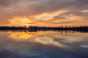Naklejka na ściany i meble Beautiful sunset with reflection of clouds on the surface of the smooth water of a wide river
