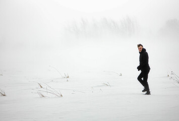 man in a warm jacket in a snowfall in a snow field.