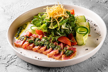 tuna slices with fresh vegetables and green beans salad on a plate.