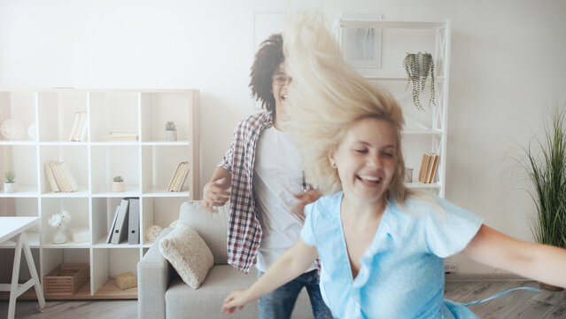 Couple fun. Crazy weekend. Happy moments. Defocused joyful excited girl dancing with boyfriend at light morning home interior with copy space. - Powered by Adobe