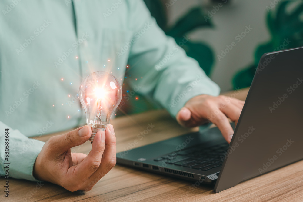 Aufkleber man holding a light bulb while working on the computer to think and create new ideas with technologi