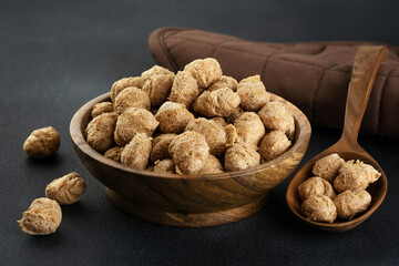 Pieces of soy meat in a wooden bowl on a dark background. Dry vegan meat.
