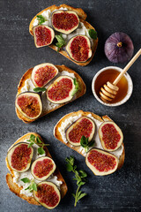 Fig bruschetta, bread and cream cheese and fruit on dark background