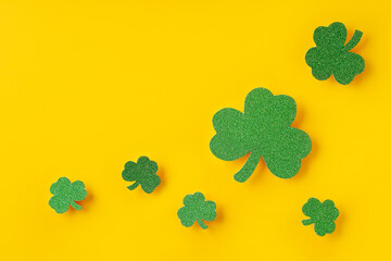 Saint Patrick day concept flat lay with green clover leaf close up on yellow background,