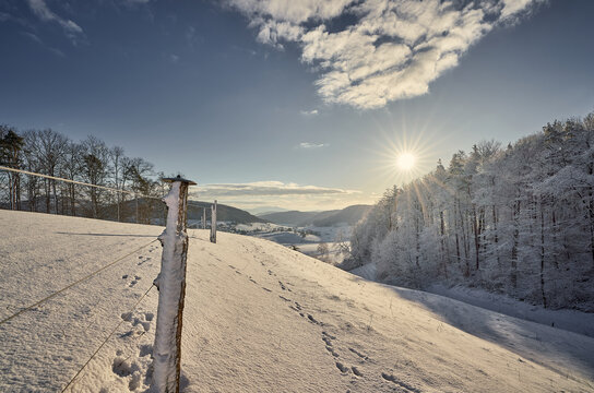 Winterlandschaft im aargauischen Fricktal. Sonnenaufgang &uuml;ber dem Wald mit Blick auf das Dorf M&ouml;hntal.