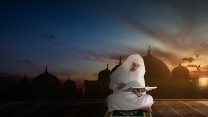 Obraz premium Muslim man sitting and reading the Quran on the prayer rug