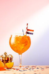 Summer coctail Aperol spritz in glass with Dutch flag and Kings day symbols in background. National holiday Koningsdag on 27 aprilin the Netherlands. Holland culture concept with copy space