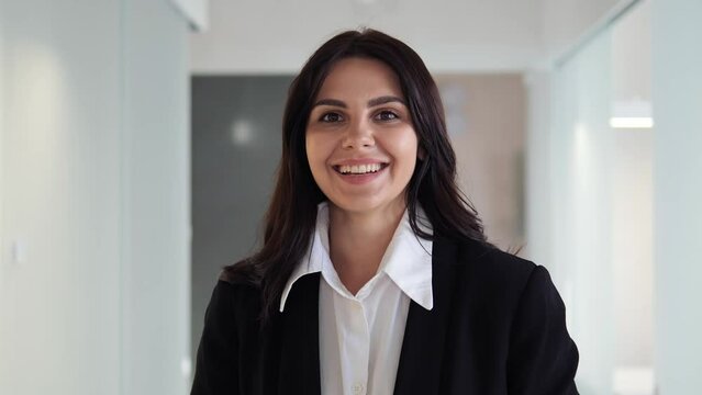 Portrait of a confident, beautiful, smiling businesswoman in office corridor. Professional woman exudes charm, intelligence, and success. Girl demonstrating her leadership skills, strong work ethic. 