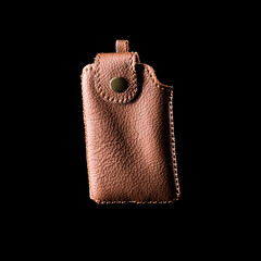 A simple brown leather keychain pouch, isolated on black background