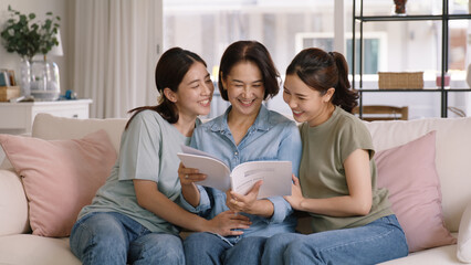 Obraz premium Buy mediclaim health care life insure for older mum. Young adult woman asia people grown up child give gift to middle aged mom reading protect cover saving plan paper smile laugh sitting at sofa home.