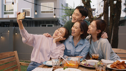 Young adult asia people hug love care for mom taking photo selfie video on mobile phone camera at home picnic dining fun night party dine table. Relax older mum smile enjoy warm time happy hour meal.