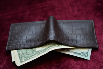 US dollar bills popping out of a leather wallet