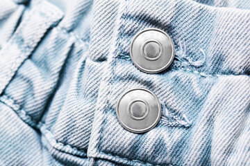 Blue jeans denim fabric. Grunge fashion background pattern with closeup on metal button. Zipper double button.