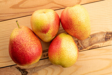 Four ripe yellow-red pears, close-up, on a wooden table.