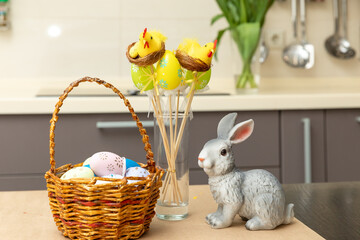 Wicker basket with bunny, tulip, easter colorful eggs on kitchen wooden table. Spring easter composition with space for text.