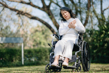 Fototapeta na wymiar Asian old woman sitting on a wheelchair outdoors in the park Have pain in the arms, wrists and body in sun light