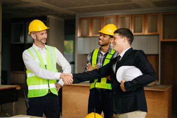 Engineers or architecture shaking hands at construction site for architectural project, holding safety helmet on their hands. successful cooperation .