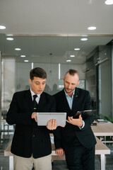 Kind leader executive manager share and discuss business solutions plan ideas on tablet with male marketing manager in modern office..