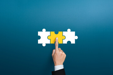 Businessman hand connecting yellow puzzle pieces. joint venture, partnership, Mergers or acquisition concept - obrazy, fototapety, plakaty
