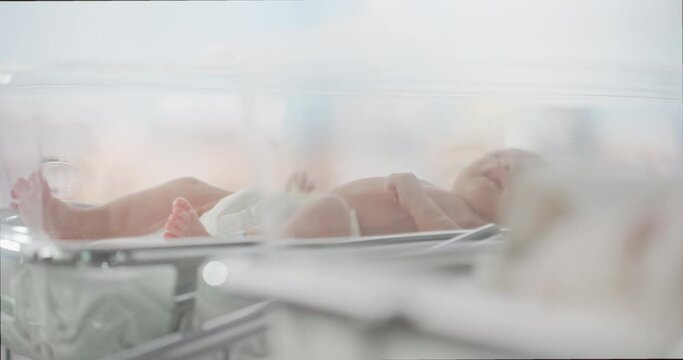 Adorable Small Caucasian Newborn Child Lying in Hospital Bed in a Nursery Clinic. Little Playful and Healthy Baby. Medical Health Care, Maternity and Parenthood Concept