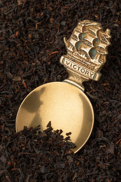 Vintage brass English Tea caddy spoon in dried Java Melange tea leaves as background