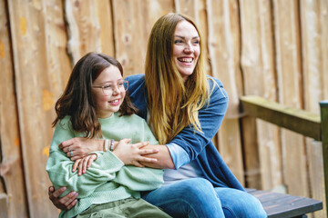 Portrait of little school girl with glasses and mother hugging together. Cute daughter and happy woman. family, childhood, happiness and people