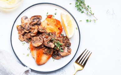 Fried chicken fillet with mushrooms and onion in white wine sauce with thyme on plate, white background, top view