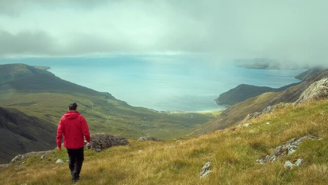 A hiker at the top of the mountain views the magnificent landscape of the sea bay. Isle of Skye. Bla Bheinn, Isle of Skye, Scotland 