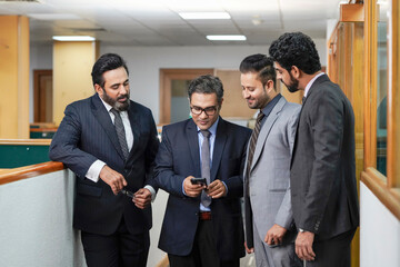 Indian businesspeople group watching some detail in smartphone and discussing at office