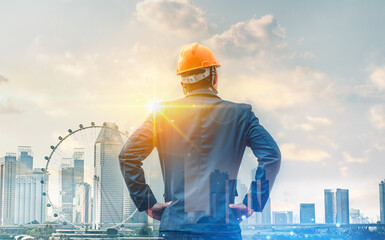 Businessman wearing yellow helmet and standing front during sunrise superimposed on cityscape.Real estate investment, Management and investment concepts.