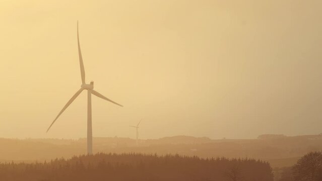 Rotating wind turbine in the countryside illuminated by sunlight at sunset. West Lothian, Scotland, United Kingdom West Lothian, Scotland, UK