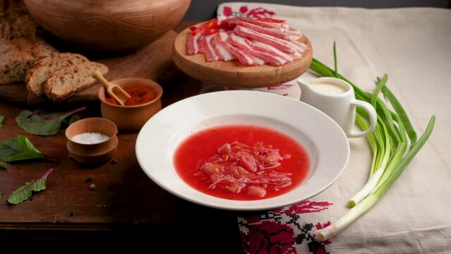 Traditional Ukrainian borscht. Bowl of red beet root soup borsch with white cream . Beet Root delicious soup. Woman serving hot Ukrainian borscht. A plate with chopped lard. Traditional Ukraine food c