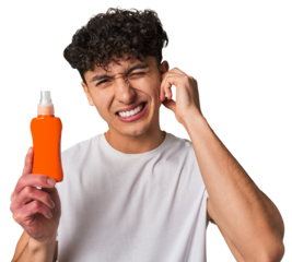 A young latin man holding a solar protection cream covering ears with hands.
