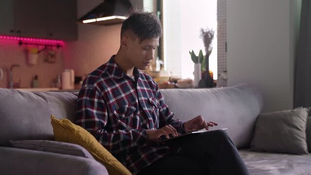 Young hipster man resting at home and making a beat on tablet. Student learning write music. Sound producer creates music at home. New digital portable audio mixing technology. Indoor sound beat maker