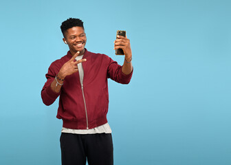 Young handsome african american man taking selfie with mobile phone on blue isolated background