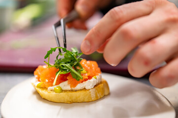 man chef hand cooking Bruschetta with salmon and cream cheese on restaurant kitchen