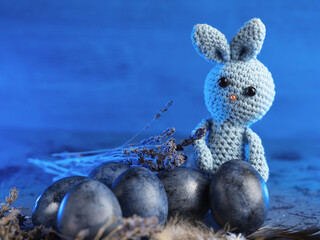Knitted bunny and Easter eggs on a dark blue background. lavender flowers