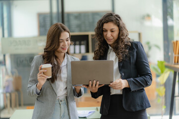Two cheerful businesswoman working using laptop computer at conference table with work documents at office. Business colleagues for meeting to discuss real estate project