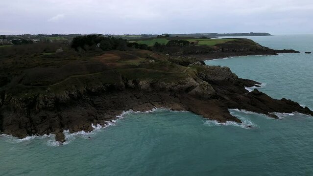 Rocky and jagged cliff with old building of Daules guardhouse between Plage du Verger and Petit Port beach, Cancale in France. Aerial sideways