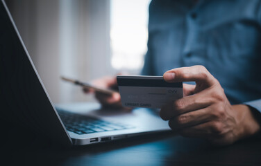Hand holding credit card for makes a purchase on the Internet on the laptop computer with credit card, online payment, shopping online, e-commerce, internet banking, spending money concept.