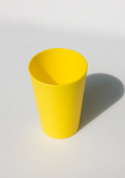 A Yellow Plastic Cup On A White Background.