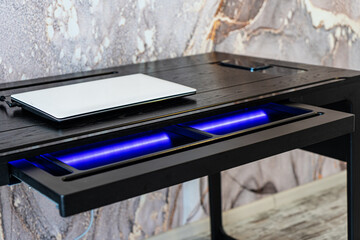 Top view of empty open wooden drawer office table with blue lightning. Modern office table with light