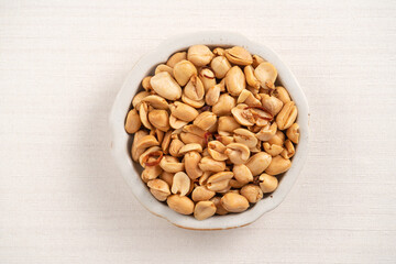 Spicy flavored peanut kernel in a bowl on white table background.