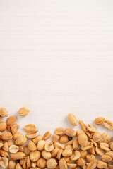 Spicy flavored peanut kernel spilling on white table background.