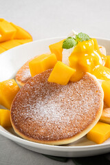 Delicious Japanese souffle pancake with dice mango and jam on gray table background.