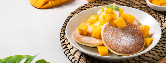Delicious Japanese souffle pancake with dice mango and jam on gray table background.