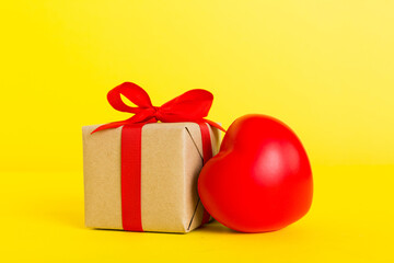 Obraz premium gift box with red bow and red heart on colored background. Perspective view. Flat lay