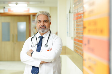 Indian male senior doctor standing at hospital.