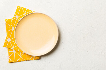 Top view on colored background empty round yellow plate on tablecloth for food. Empty dish on...