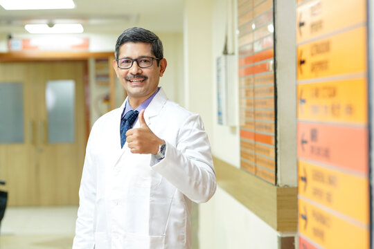 Indian male doctor showing thumps up at hospital.